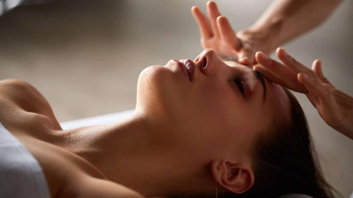 Visage de femme allongée qui avec deux mains qui lui massent le front