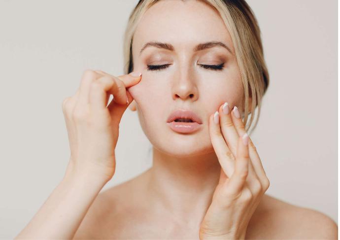 Femme blonde yeux fermés qui se masse les joues