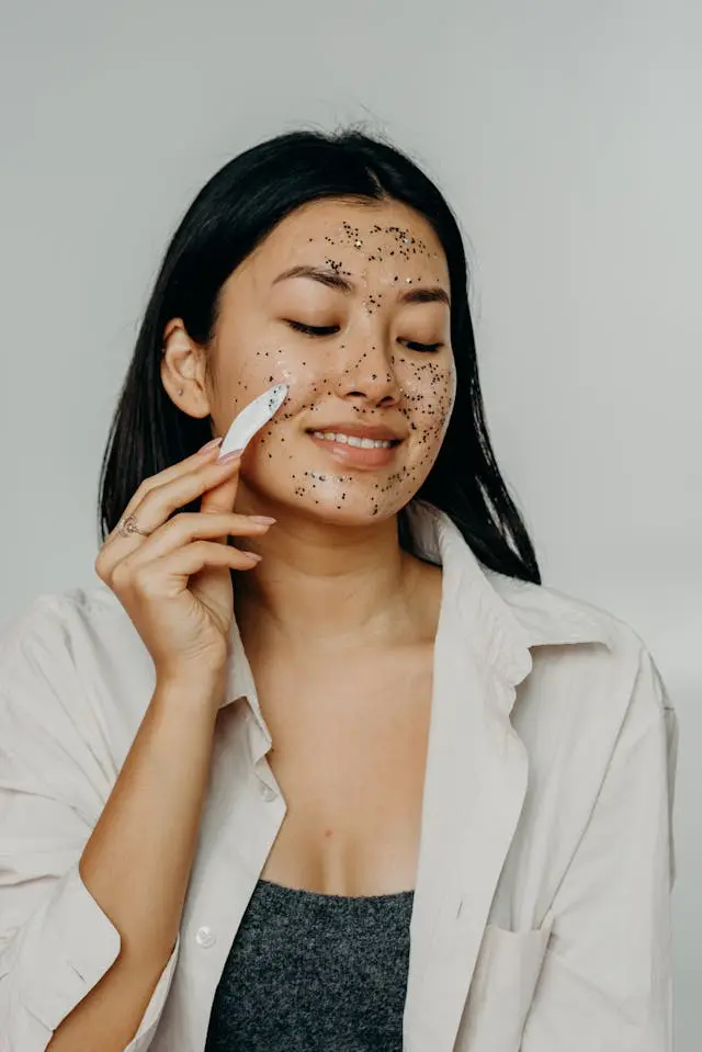 Jeune femme brune avec exfoliant grains noirs sur le visage