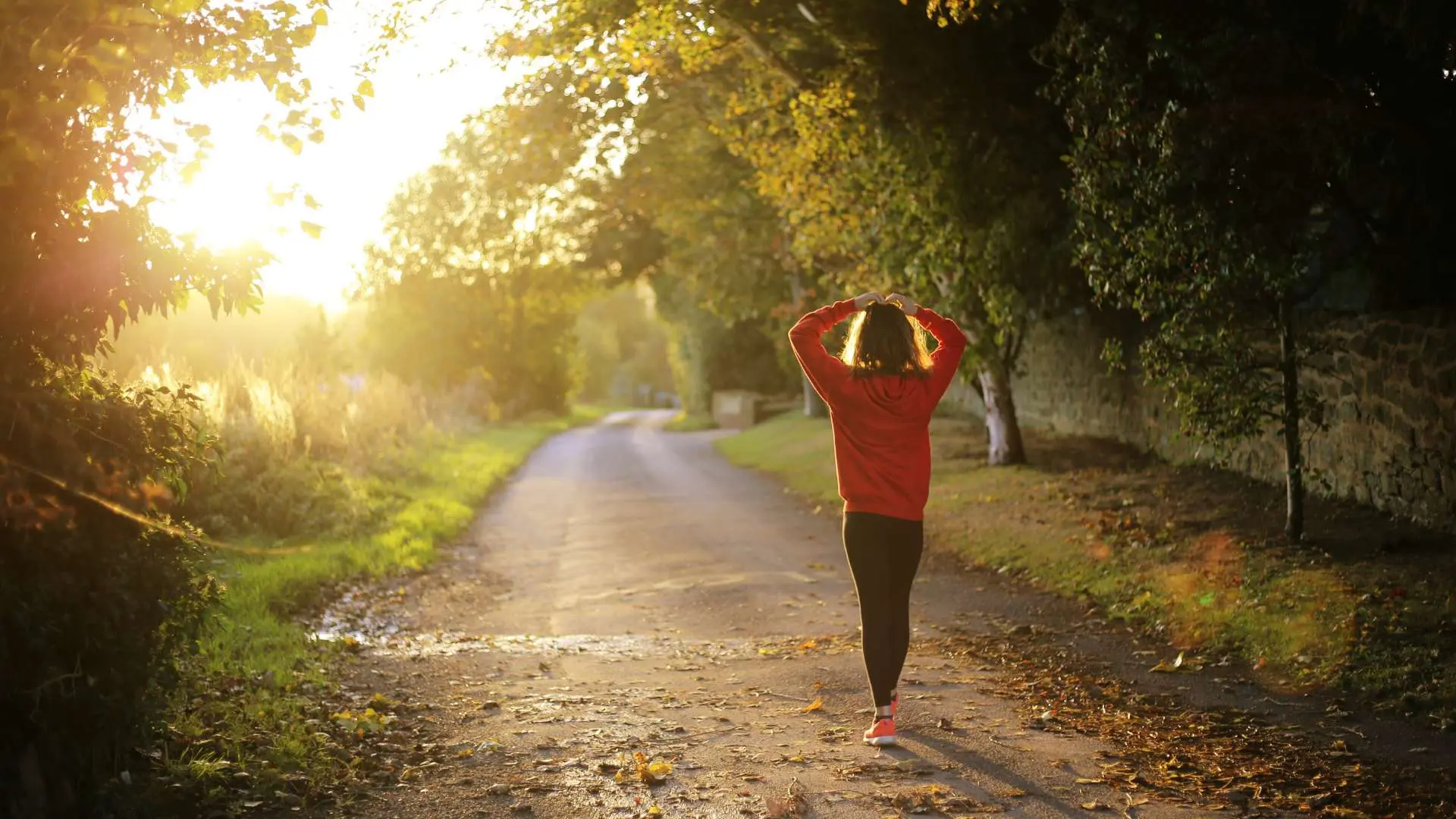 Femme de dos legging noir et sweat rouge sur un chemin de  campagne